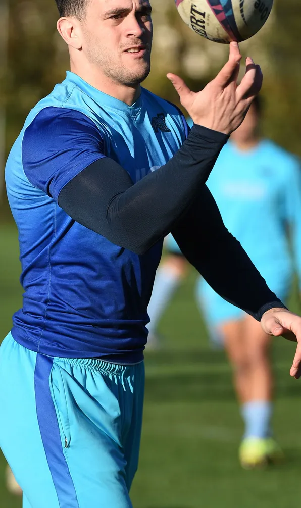 Mens Base Layers & Compression Male rugby player wearing a blue rugby shirt with a black baselayer top throwing the ball in the air