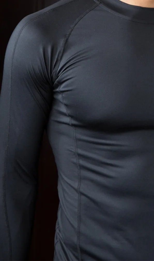Teamwear Rugby Baselayer A model wears a tight fitting black baselayer top standing next to a black background