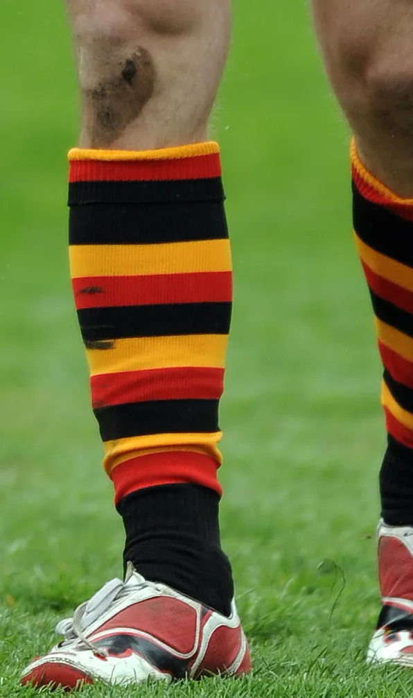 Teamwear Rugby Socks A rugby player with black, yellow and red striped rugby socks pulled up