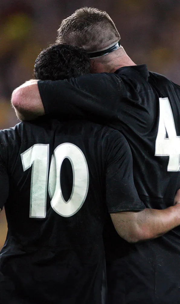 Shop Gifts for Him Now Two All Blacks players hugging each other, celebrating a win