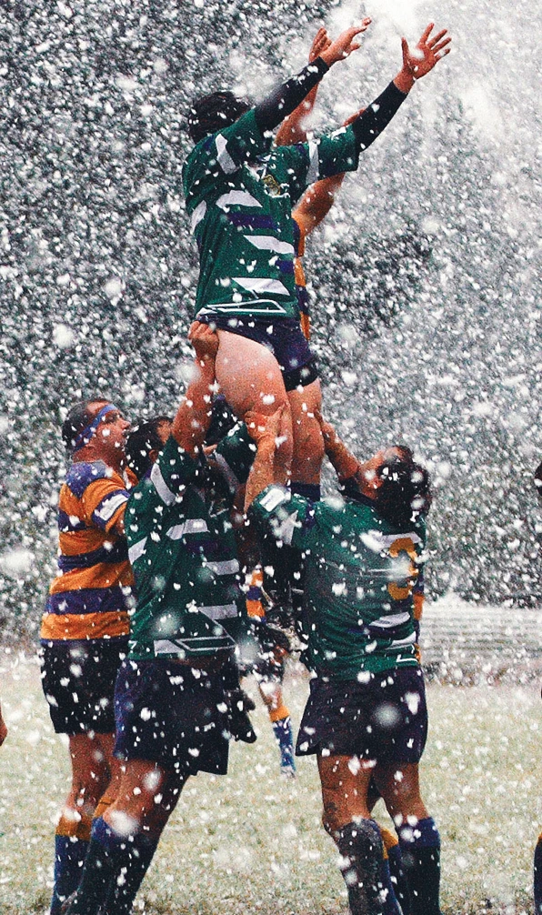 Two rugby teams jump for the ball in a lineout on a very snow rugby pitch