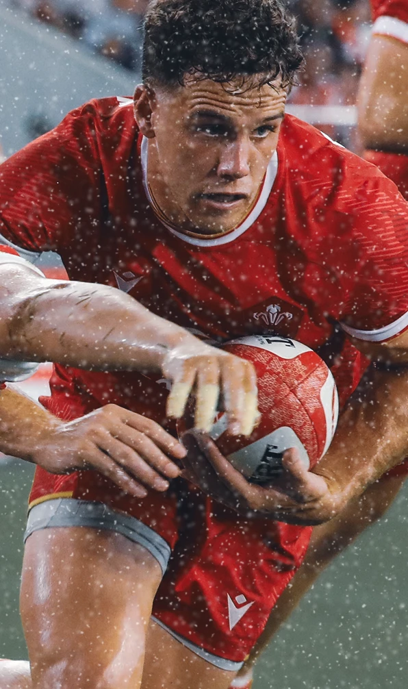 A Wales Rugby player runs through a tackle, his eyes fixed firmly on the try line