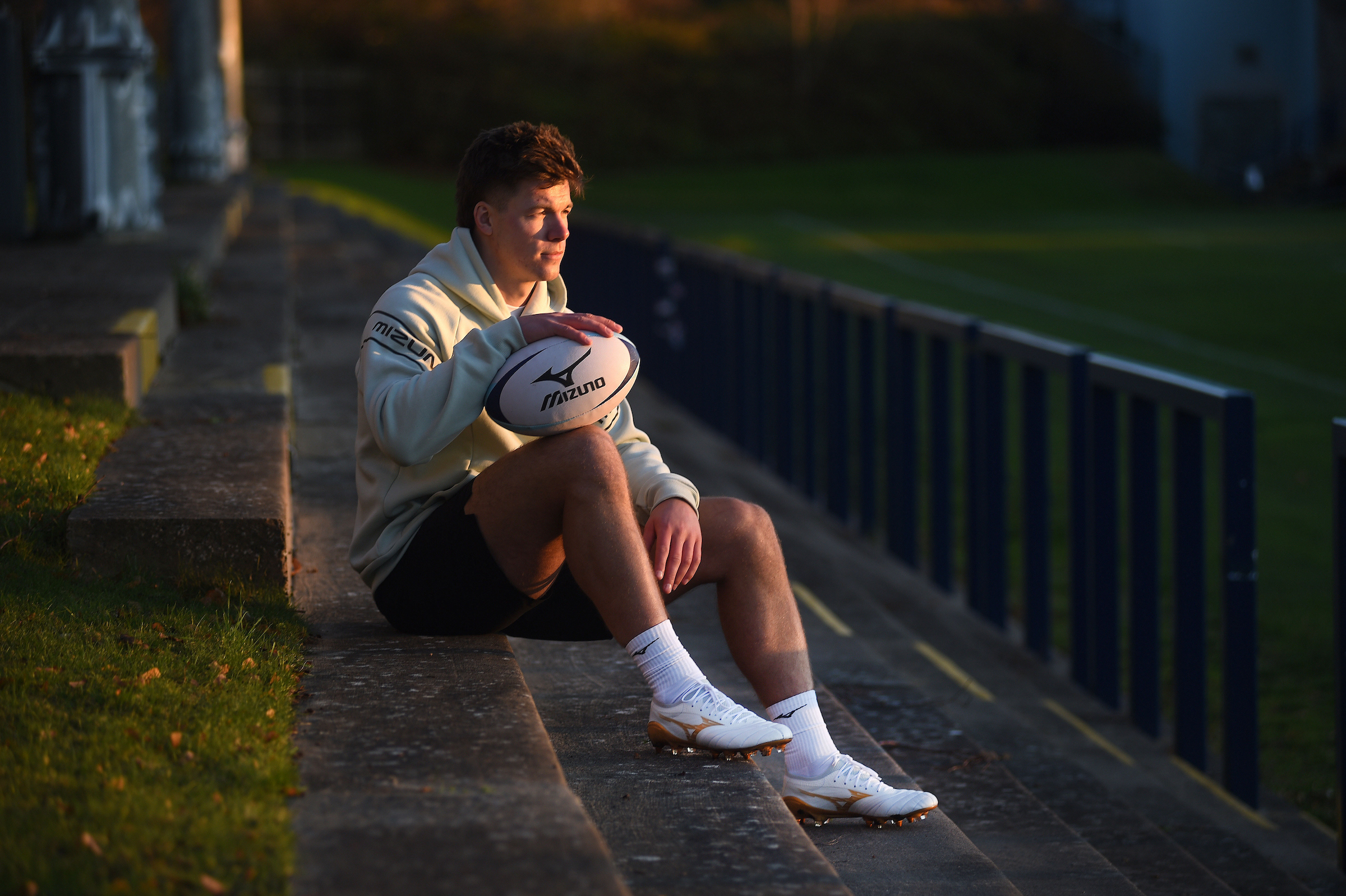 Huw Jones Mizuno Bright Gold Pack Photoshoot Huw Jones sitting in the Mizuno Bright Gold Pack rugby boots