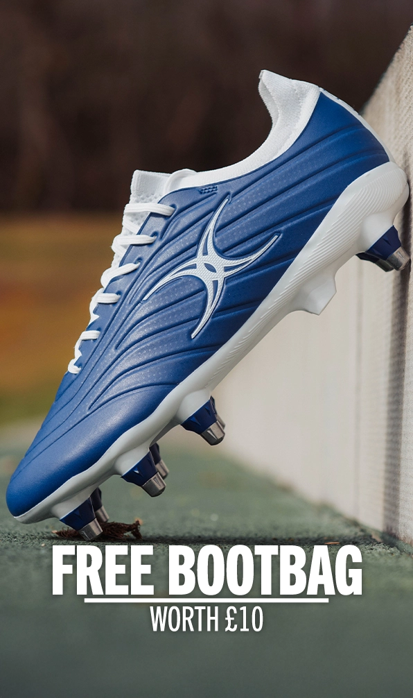 The latest pair of Gilbert rugby boots on the side of a training field.