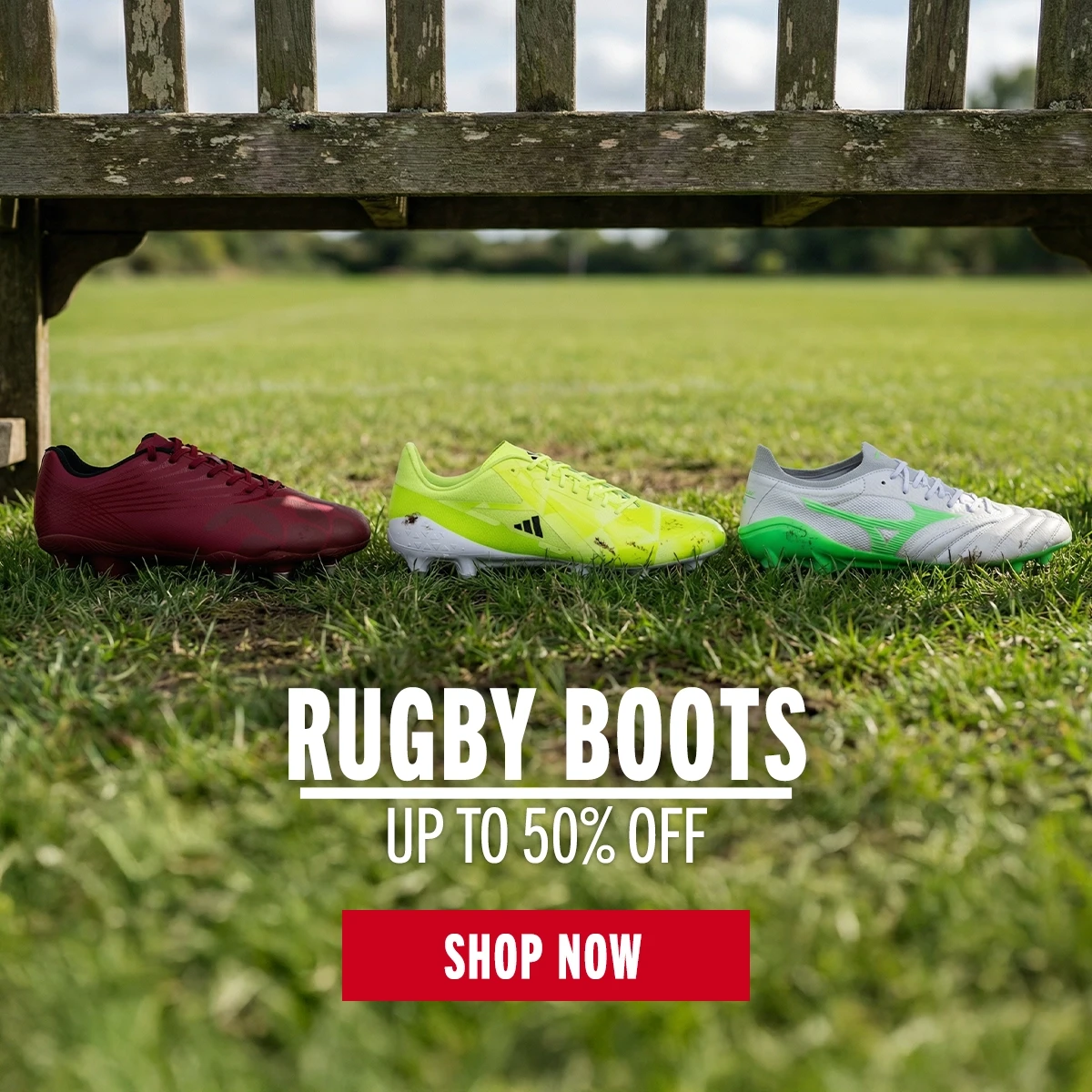 UP TO 50% OFF RUGBY BOOTS! Three rugby boots displayed in front of a bench at the side of a rugby pitch. They are one each from Canterbury, Adidas and Mizuno