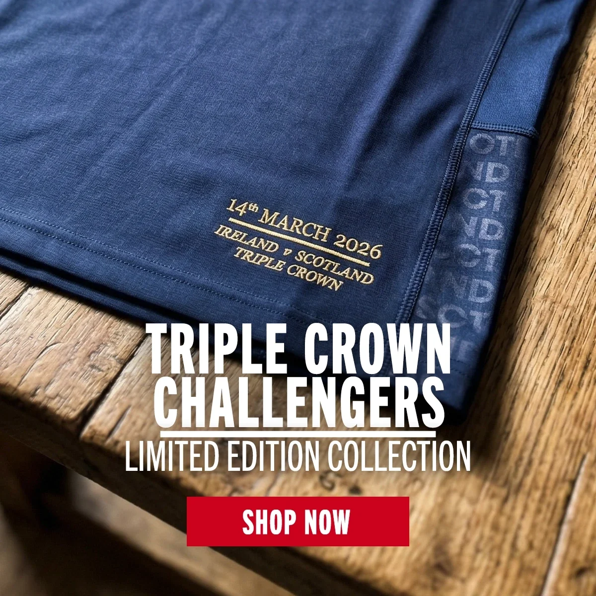 A Scotland rugby jersey laying on an old wooden table showing only the hem, which has limited edition embroidery on it.