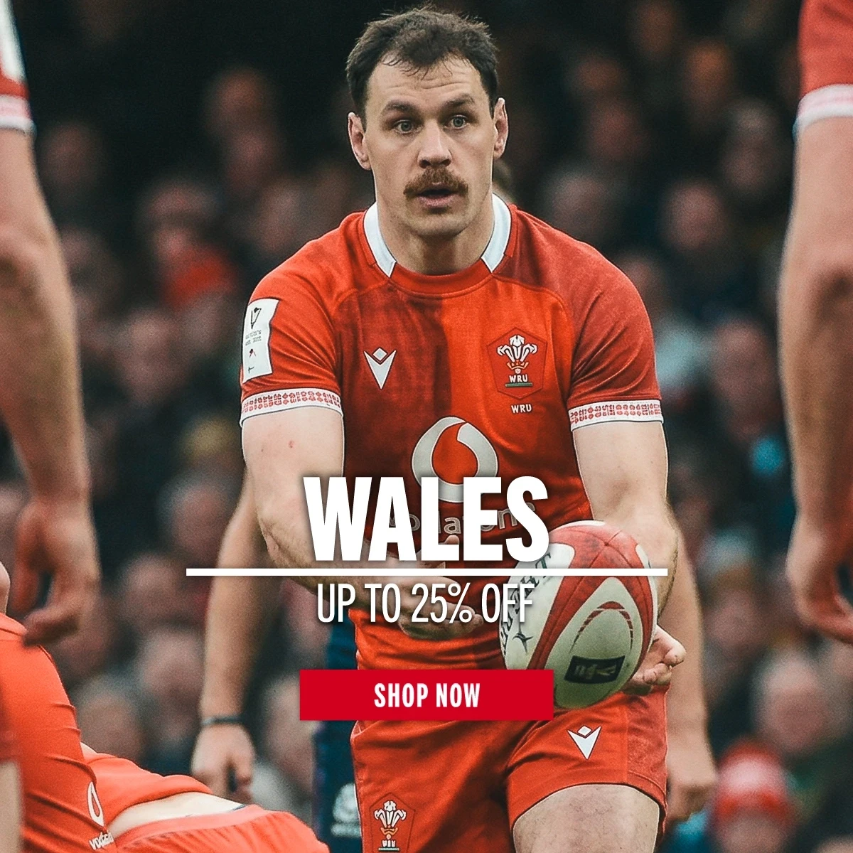 Wales rugby player Tomos Williams passes the ball to a team mate. A large crowd of fans is behind him.