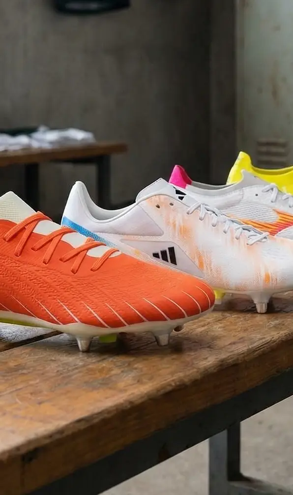 A close up image of a range of rugby boots sitting on a wooden bench.