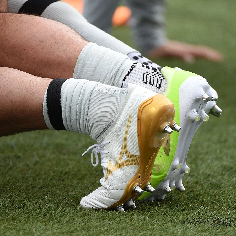 Two players get ready to engage in scrum training as you see the soleplates of the their respective Mizuno and Adidas boots.