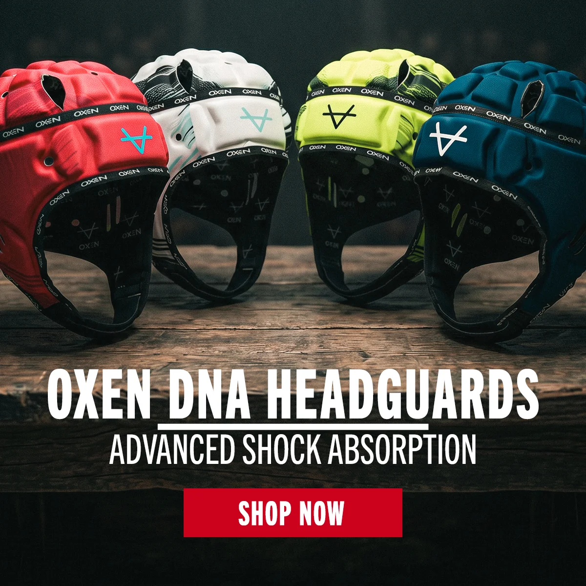 Four Oxen rugby headguards sit arranged in a semicircle on a table. The lighting is moody, dark and shadowy