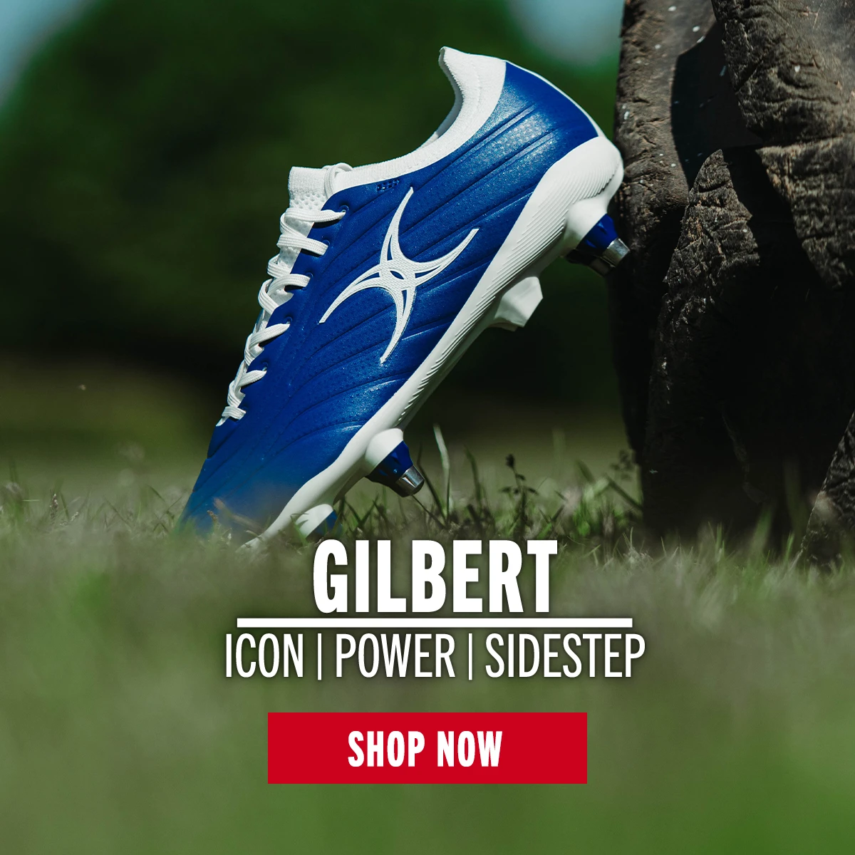 A Gilbert rugby boot sits on the side of a tyre on a sunny day.