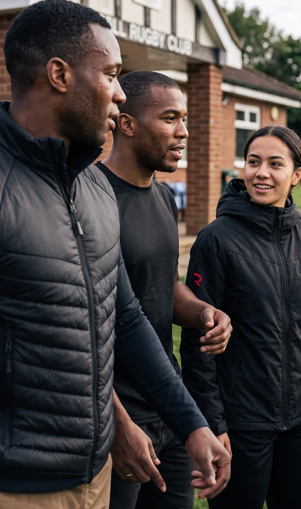 Three people walk onto a rugby field wearing various clothing garments from the Rugbystore Performance Training & Teamwear collection.